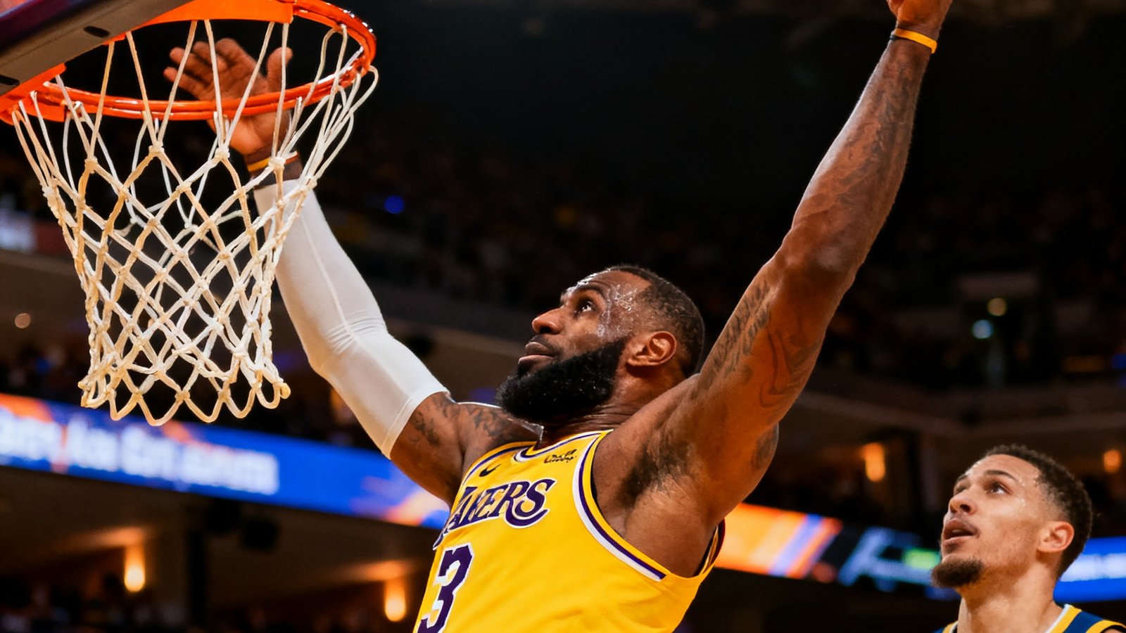湖人对阵勇士的NBA比赛视频集锦封面图，一名球员正在完成高难度扣篮动作，球场灯光聚焦在篮筐区域